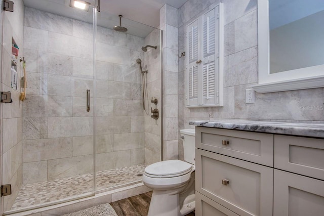 bathroom featuring wood-type flooring, toilet, and a shower with shower door