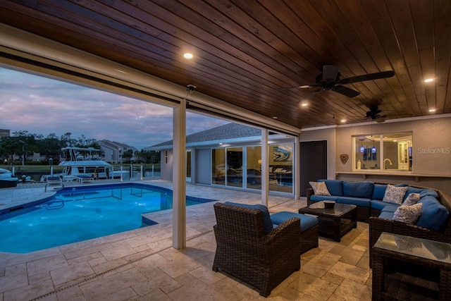 pool at dusk featuring ceiling fan, an outdoor hangout area, and a patio