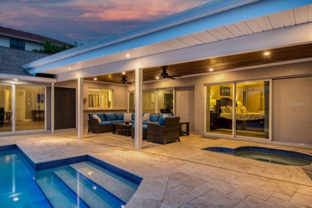 pool at dusk with an in ground hot tub, an outdoor hangout area, ceiling fan, and a patio area