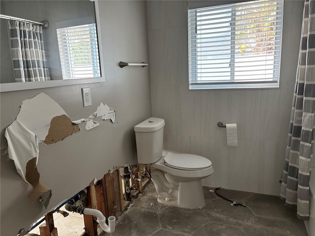 bathroom with curtained shower, toilet, and tile walls