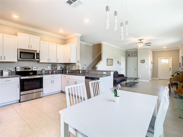 kitchen with pendant lighting, white cabinets, ceiling fan, ornamental molding, and stainless steel appliances