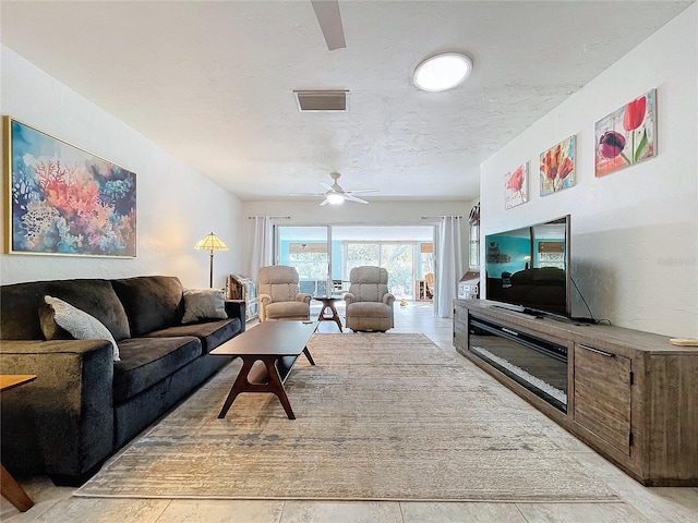 living room featuring ceiling fan and a textured ceiling