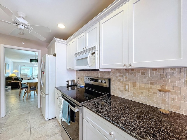 kitchen with backsplash, white appliances, light tile patterned floors, dark stone countertops, and white cabinetry