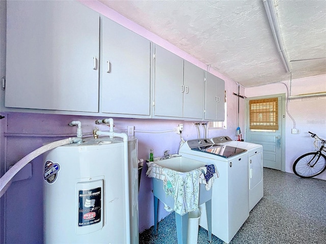 clothes washing area featuring cabinets, a textured ceiling, water heater, and washing machine and clothes dryer