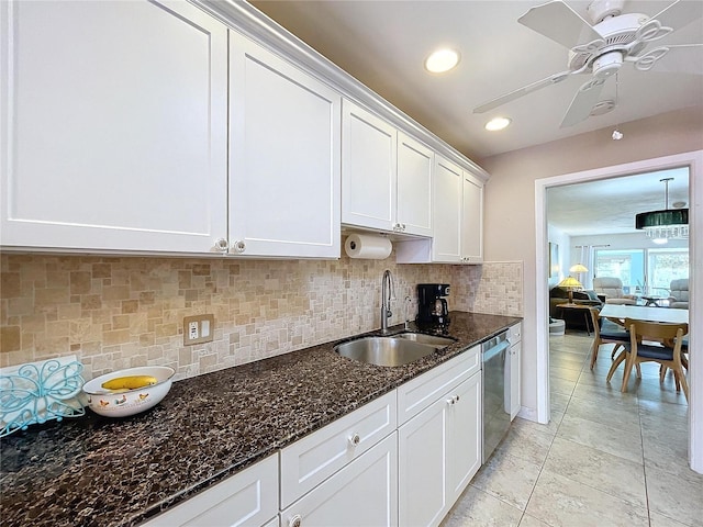 kitchen featuring decorative backsplash, dark stone counters, sink, dishwasher, and white cabinetry