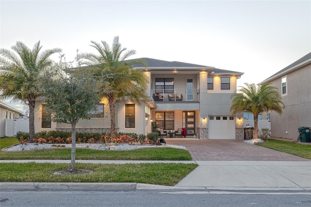 view of front of house featuring a balcony, a garage, and a front lawn