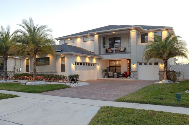 view of front of home featuring a balcony, a front lawn, and a garage