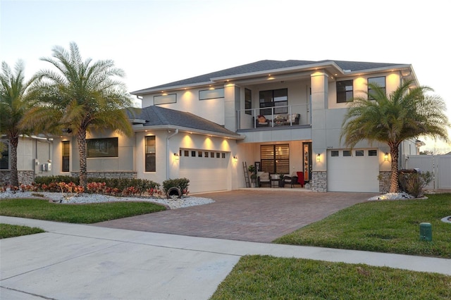 2436 Chateau Loop, Kissimmee, FL 34741 - view of front of property with a balcony, decorative driveway, stucco siding, stone siding, and an attached garage