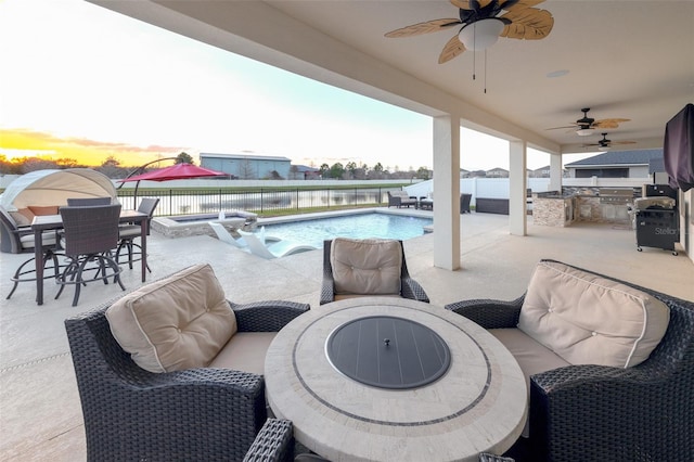 patio terrace at dusk featuring a pool with hot tub, a water view, and an outdoor kitchen