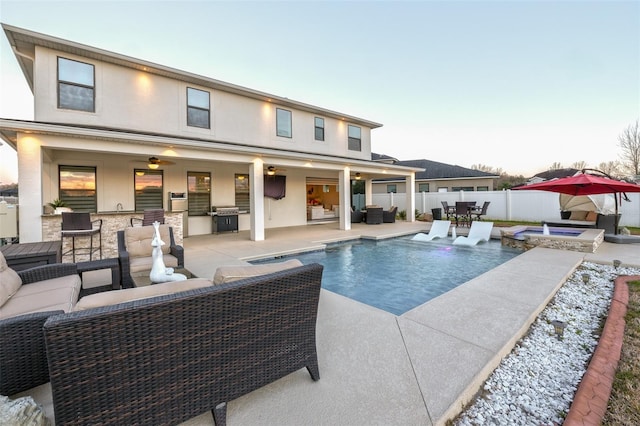 pool at dusk with exterior kitchen, an outdoor living space, area for grilling, an in ground hot tub, and a patio