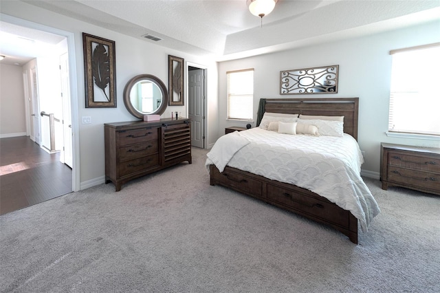 bedroom featuring a textured ceiling, light colored carpet, multiple windows, and ceiling fan