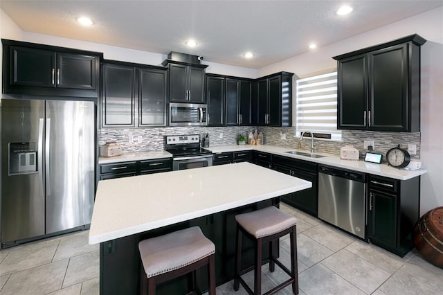 kitchen with appliances with stainless steel finishes, tasteful backsplash, sink, a center island, and a breakfast bar area