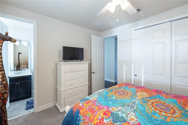 carpeted bedroom with ensuite bath, ceiling fan, and a closet