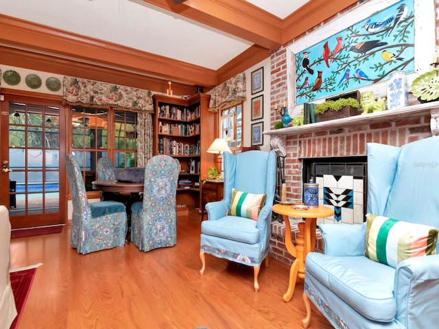 sitting room with beam ceiling, a fireplace, ornamental molding, and hardwood / wood-style flooring