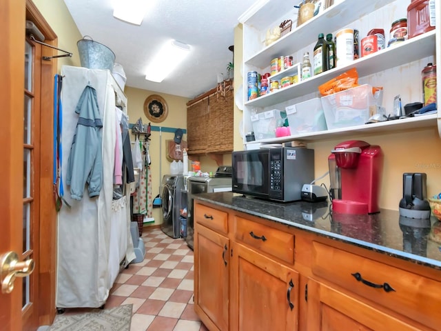 kitchen with washing machine and dryer and dark stone counters