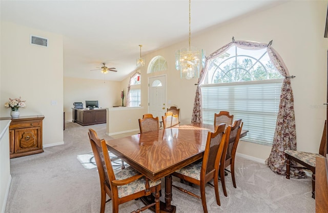 carpeted dining space featuring lofted ceiling, a healthy amount of sunlight, and ceiling fan with notable chandelier