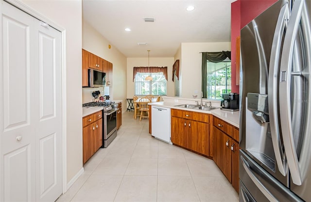 kitchen with appliances with stainless steel finishes, light tile patterned floors, pendant lighting, and sink