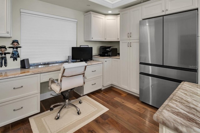 office space with crown molding, built in desk, and dark wood-type flooring