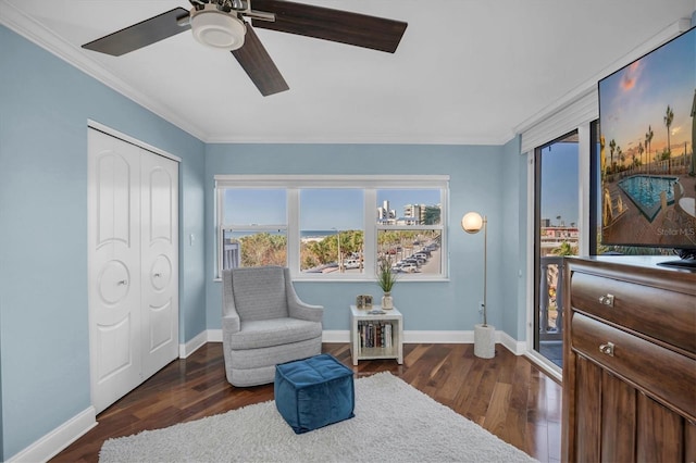 living area with dark hardwood / wood-style floors, ceiling fan, and crown molding