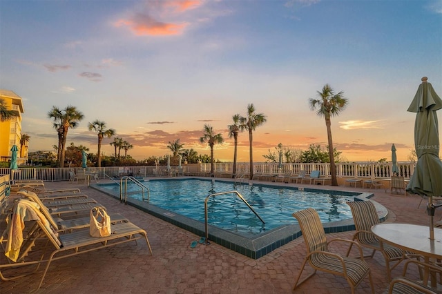 pool at dusk featuring a patio