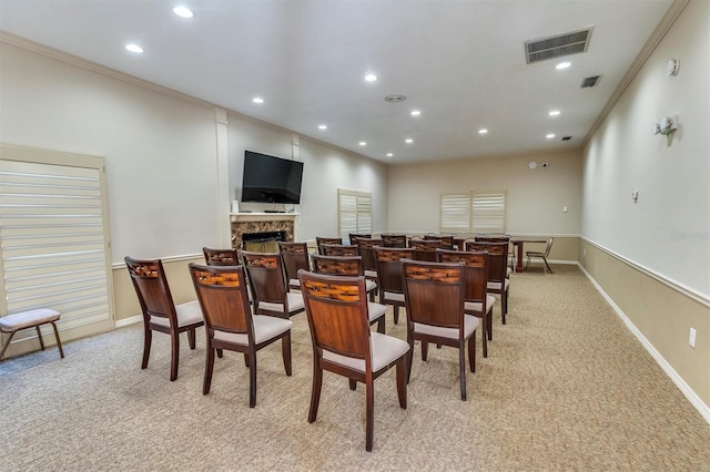 dining area with a fireplace, crown molding, and light carpet