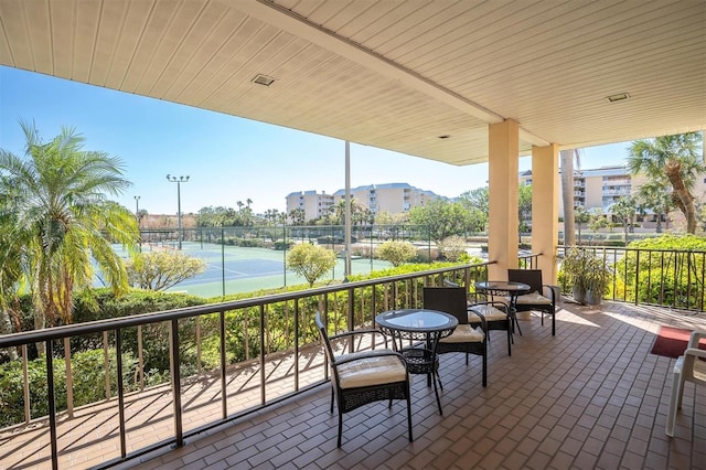 view of patio / terrace featuring tennis court and a water view