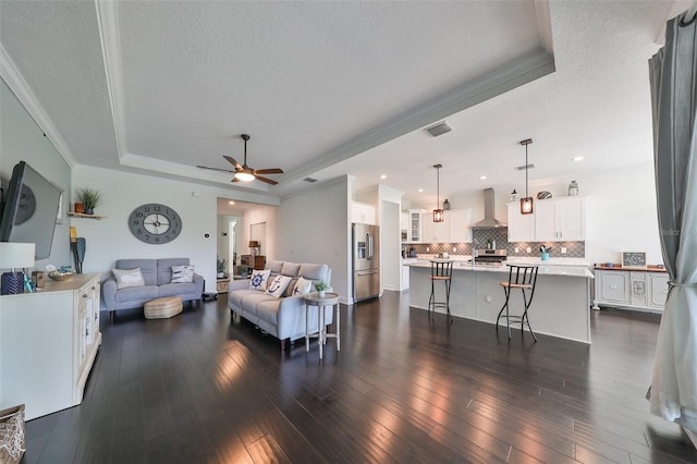 living room featuring a tray ceiling, ceiling fan, dark hardwood / wood-style flooring, and a textured ceiling