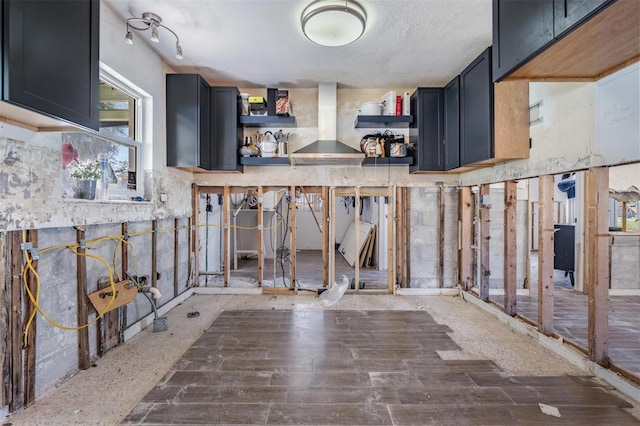 kitchen with a textured ceiling and wall chimney exhaust hood