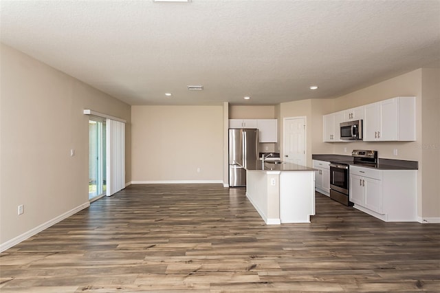 kitchen with a center island with sink, white cabinets, sink, dark hardwood / wood-style flooring, and stainless steel appliances