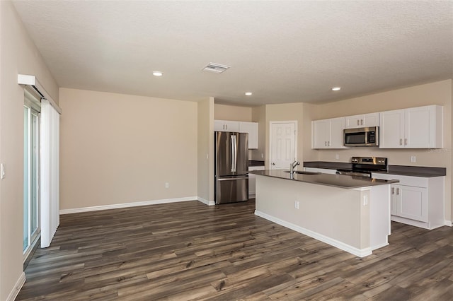 kitchen with white cabinetry, a kitchen island with sink, dark hardwood / wood-style flooring, and appliances with stainless steel finishes