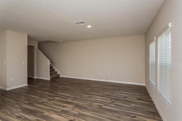 spare room with a textured ceiling and dark hardwood / wood-style flooring