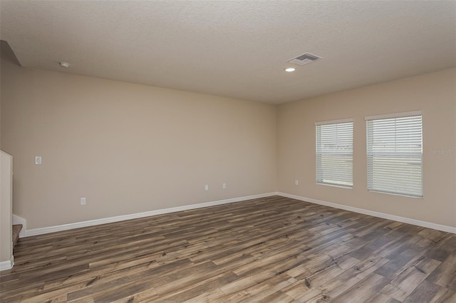 unfurnished room with a textured ceiling and dark hardwood / wood-style floors