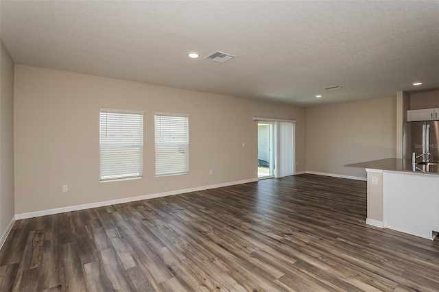 unfurnished living room with a textured ceiling and dark hardwood / wood-style floors