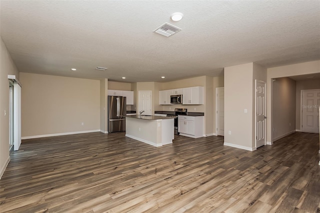 kitchen featuring white cabinets, a textured ceiling, an island with sink, dark hardwood / wood-style flooring, and stainless steel appliances