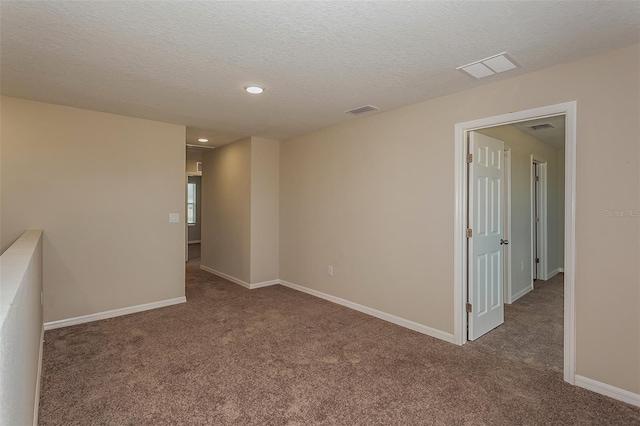 carpeted empty room with a textured ceiling