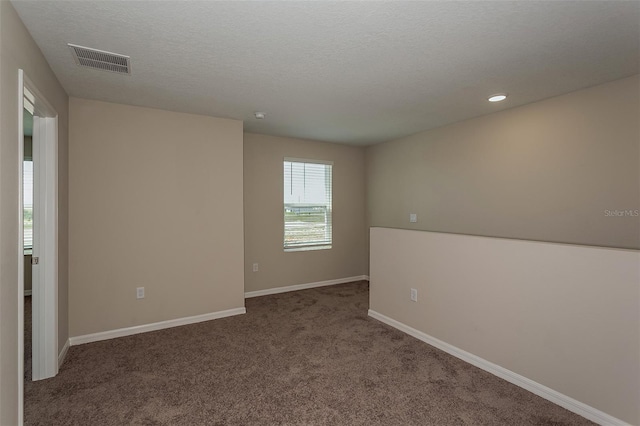 unfurnished room featuring carpet and a textured ceiling