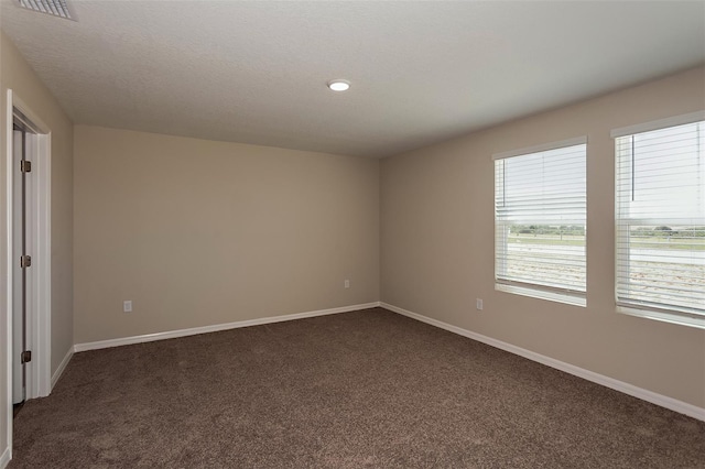 empty room with a textured ceiling and dark carpet