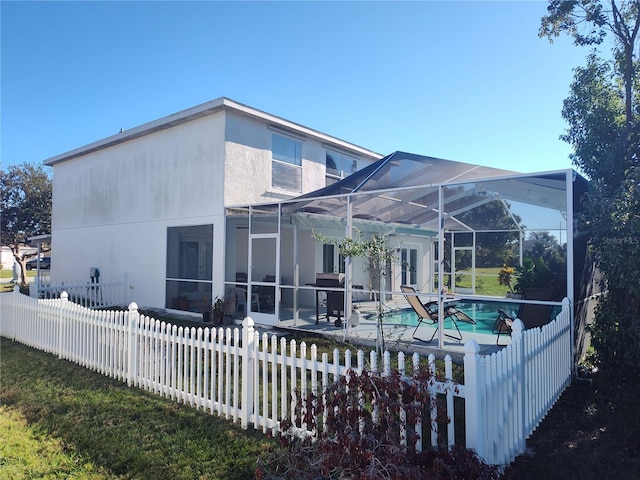 rear view of property featuring a fenced in pool and glass enclosure