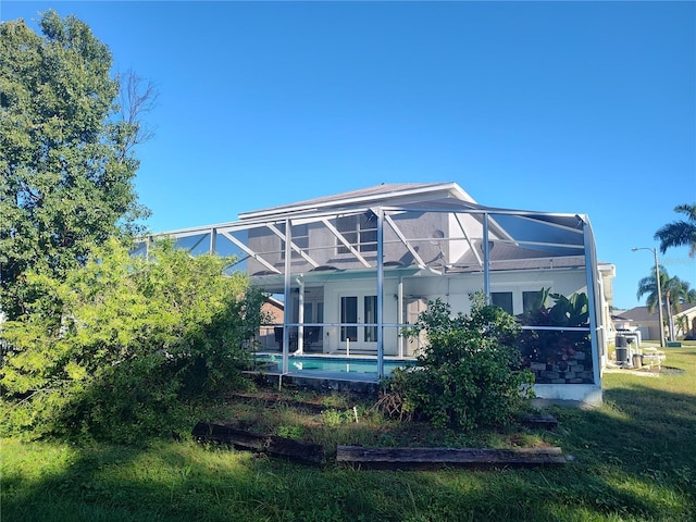 back of property featuring a lanai and a lawn