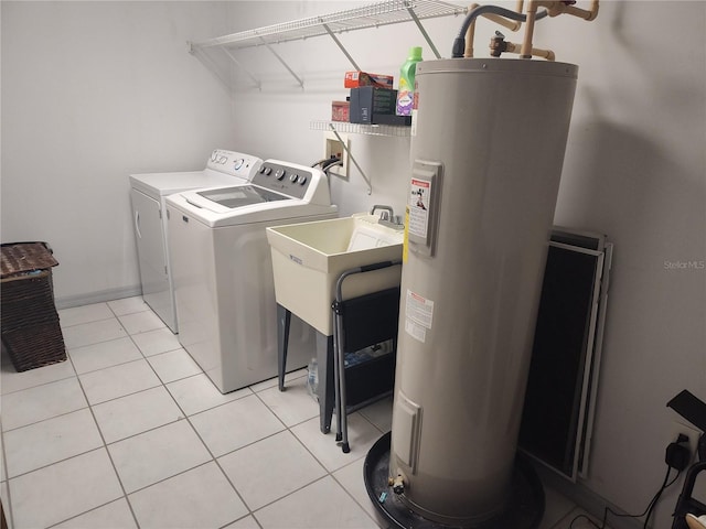 clothes washing area featuring light tile patterned floors, electric water heater, washing machine and dryer, and sink