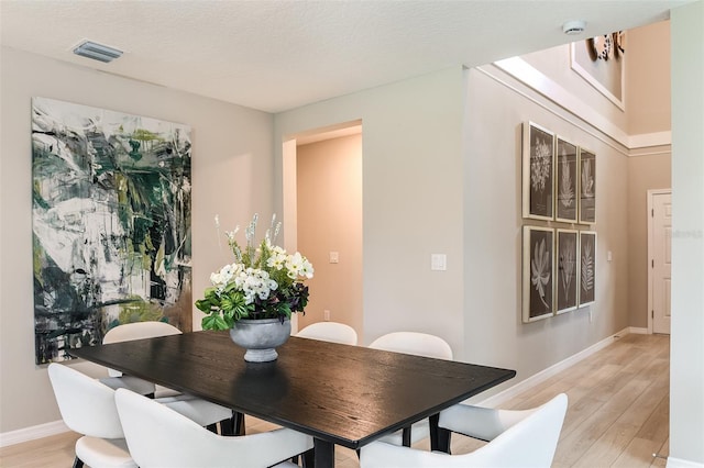 dining area with a textured ceiling and light hardwood / wood-style flooring