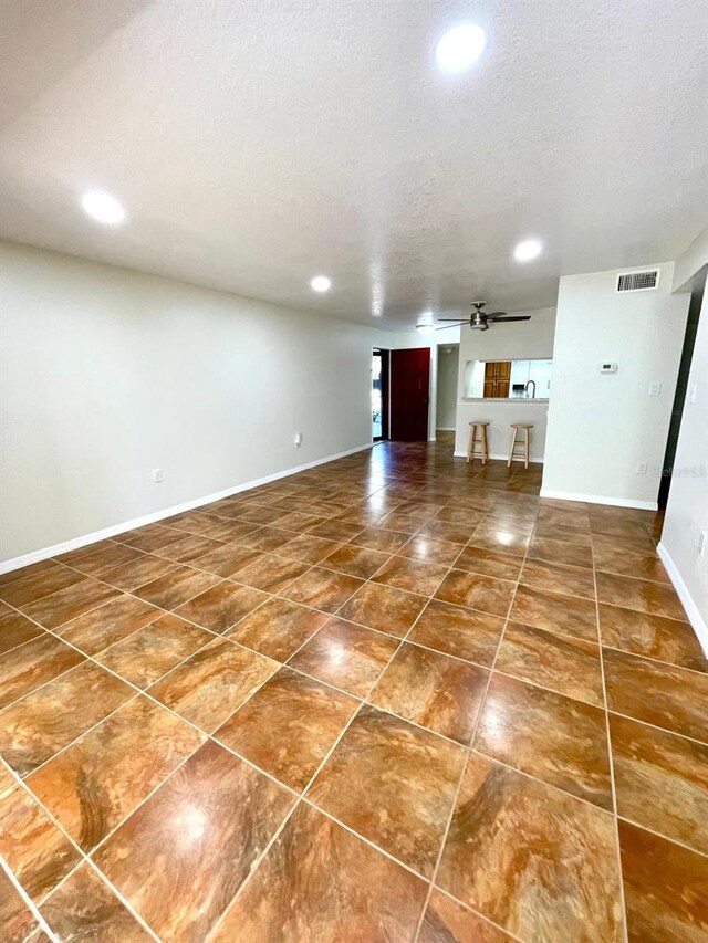 unfurnished living room with a textured ceiling and ceiling fan