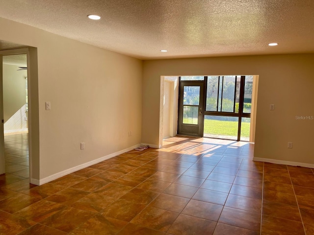 tiled spare room with ceiling fan and a textured ceiling