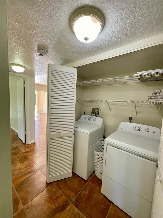 washroom featuring washing machine and dryer, dark tile patterned floors, and a textured ceiling