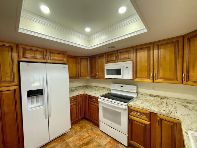 kitchen with a tray ceiling, light stone counters, white appliances, and ornamental molding