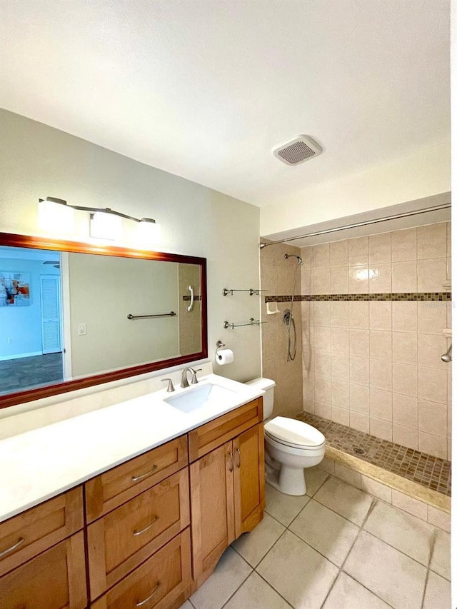 bathroom with tile patterned flooring, vanity, tiled shower, and toilet