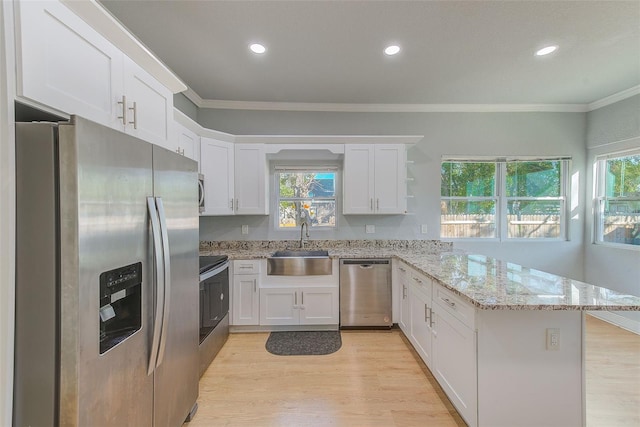 kitchen featuring appliances with stainless steel finishes, light hardwood / wood-style floors, light stone counters, and plenty of natural light