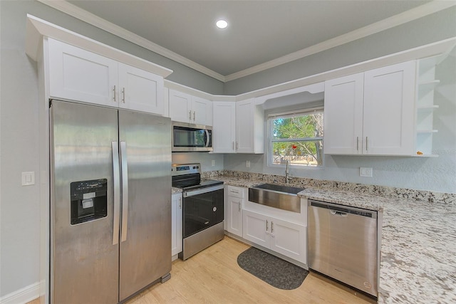 kitchen featuring appliances with stainless steel finishes, light hardwood / wood-style floors, white cabinetry, and sink