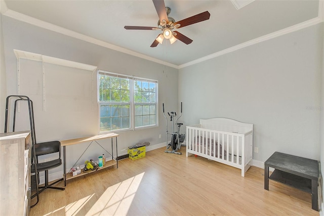 bedroom featuring hardwood / wood-style floors, a nursery area, crown molding, and ceiling fan