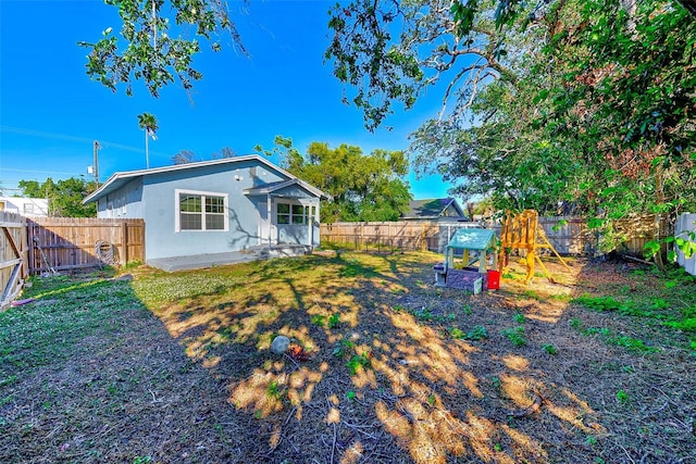 rear view of house featuring a playground and a lawn